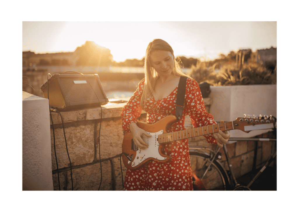 Woman in red polka dot dress playing electric guitar