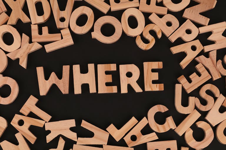 Wooden letters on black background spelling 'WHERE', showcasing typography design.